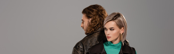 Panoramaaufnahme der attraktiven Frau in Weste und des Mannes in Lederjacke isoliert auf grau - Foto, Bild