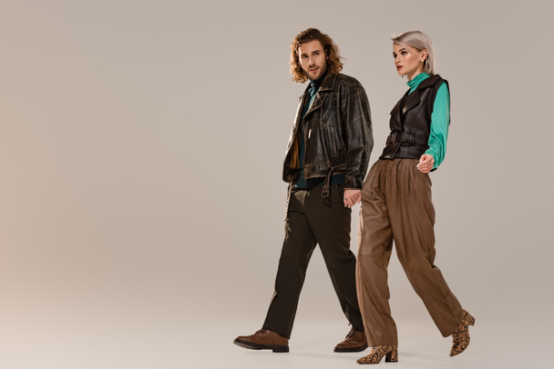 woman in vest and man in leather jacket walking on grey background  - Foto, immagini