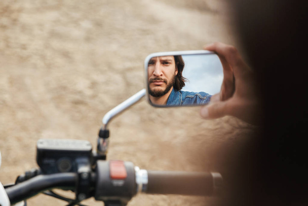 Man biker on his bike outdoors on a beach. Focus on mirror. - Photo, image