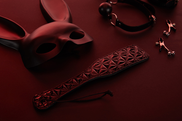 Sexspielzeug in dunkler Beleuchtung auf rotem Hintergrund - Foto, Bild