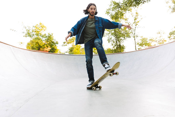 Handsome young hipster man skating on a skate ramp - Photo, image