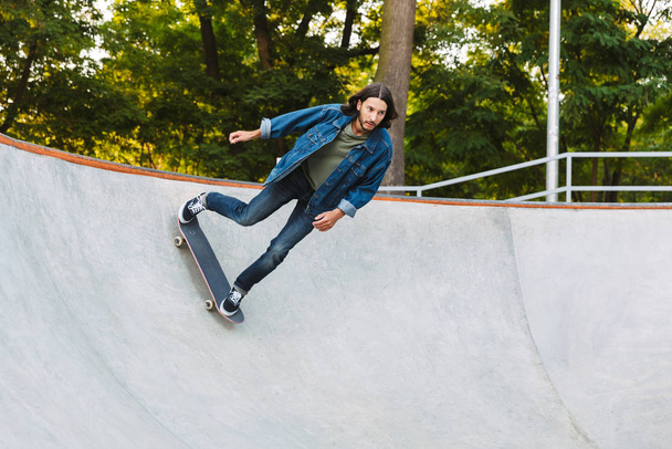 Handsome young hipster man skating on a skate ramp - Zdjęcie, obraz