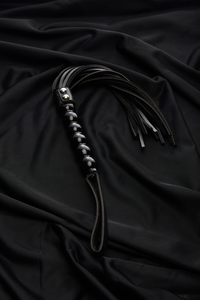 látigo azotes de cuero sobre fondo textil negro
 - Foto, imagen