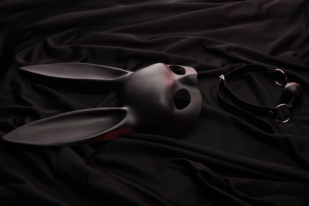 rabbit mask and gag on black textile background - Fotoğraf, Görsel