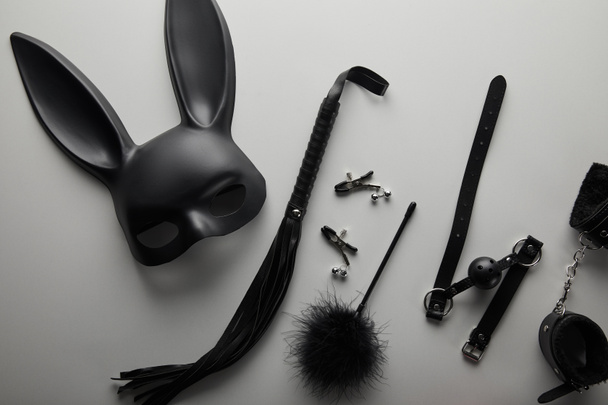 Beyaz arka planda siyah tavşan maskesi ve seks oyuncakları. - Fotoğraf, Görsel