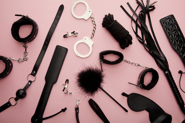 bovenaanzicht van zwart seksspeeltjes op roze achtergrond - Foto, afbeelding