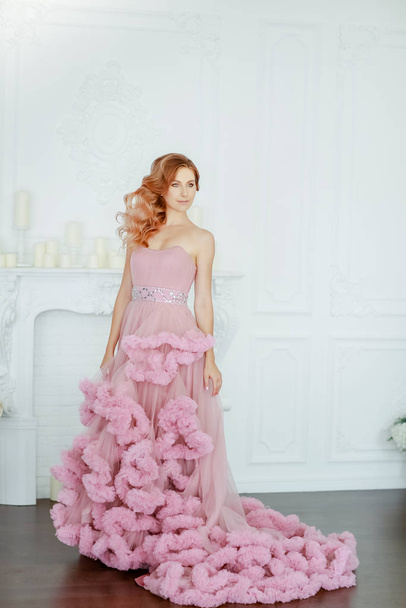 Female model in a lush pink wedding dress in full growth on a background of white room - Fotoğraf, Görsel