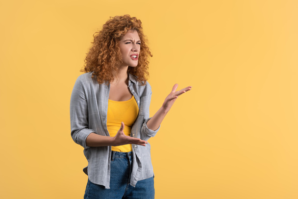 aggressive emotional redhead girl, isolated on yellow - Foto, immagini