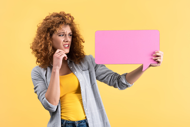 worried woman looking at empty pink speech bubble, isolated on yellow   - Foto, imagen