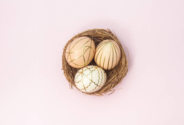 Easter eggs in a nest on a pink pastel background. Beautiful festive background, religious concept. - Фото, изображение
