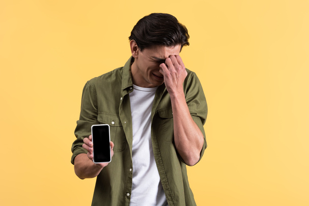 surullinen itkevä nuori mies osoittaa älypuhelin tyhjä näyttö, eristetty keltainen
 - Valokuva, kuva