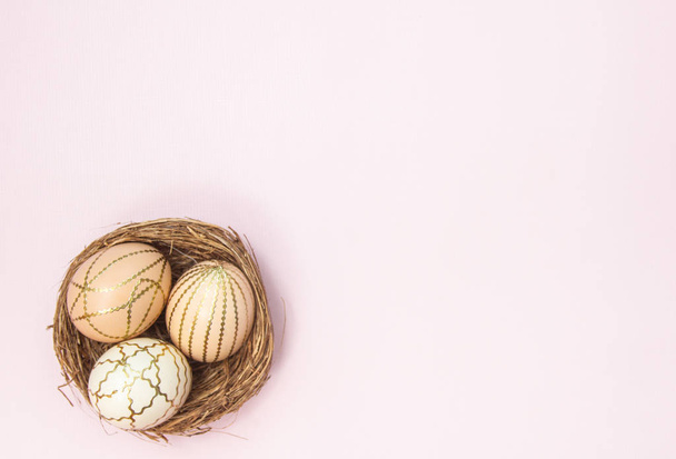 Ostereier in einem Nest auf rosa Pastellgrund. schöner festlicher Hintergrund, religiöses Konzept. - Foto, Bild