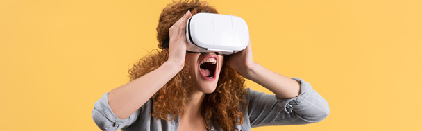 panoramatický záběr křičící emocionální dívka pomocí sluchátek virtuální reality, izolované na žluté - Fotografie, Obrázek