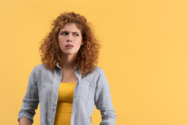 confused redhead young woman, isolated on yellow - Foto, Imagem