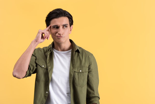 skeptical brunette young man thinking isolated on yellow - Photo, Image