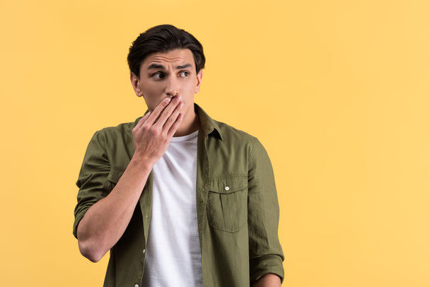 shocked man in casual clothes closing mouth, isolated on yellow - Foto, Bild