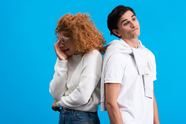 crying girlfriend and skeptical boyfriend standing back to back, isolated on blue - Foto, Bild