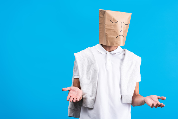 skeptical man with sad paper bag on head, isolated on blue - Foto, Imagen