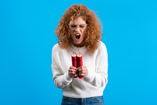 angry yelling woman in eyeglasses holding dynamite, isolated on blue - Photo, Image