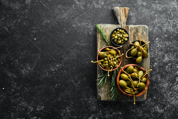 Capers. Marinated capers in a bowl on a black stone background. Top view. Free space for your text. - Φωτογραφία, εικόνα