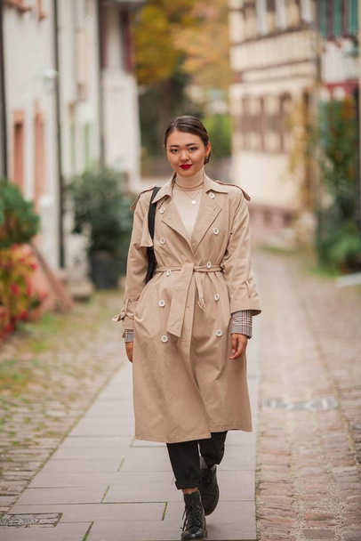 Güzel genç bir Asyalı kadın bir Avrupa şehrinde yürüyor. Genç Asyalı bir kadının modaya uygun portresi. Blogcu. - Fotoğraf, Görsel