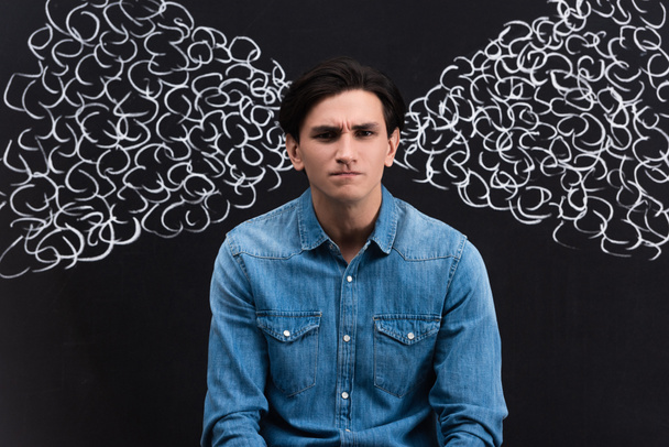 aggressive young man with steam drawing on blackboard behind - Photo, Image