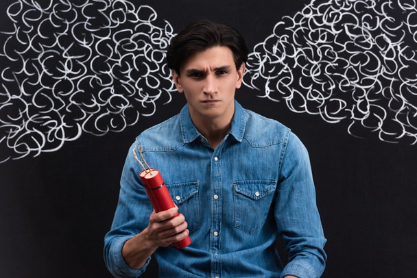 Wütender junger Mann hält Dynamit in der Hand, mit Dampfzeichnung auf Kreidetafel - Foto, Bild