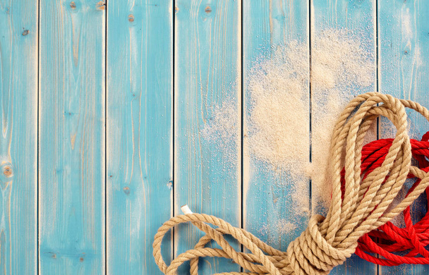 Nautical Themed Background of Bundles of Natural and Red Rope on Painted Blue Wood Background with Sand and Copy Space - Foto, imagen