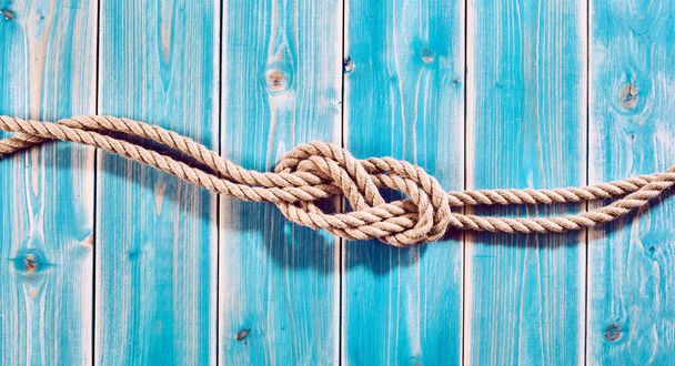 Nautical Themed Background - High Angle Still Life of Double Figure Eight Knot in Natural Rope Across Blue Painted Wood Plank Background with Copy Space - Foto, Imagem