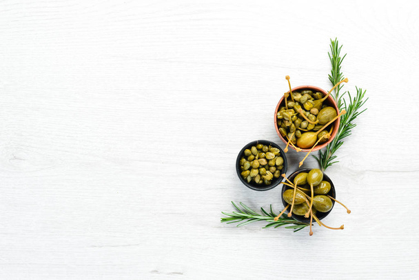 Marinated capers in a bowl on a white wooden background. Top view. Free space for your text. - Valokuva, kuva