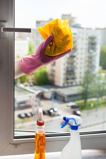 washing home window in spring - washer wipes window frame by rag in apartment house - Foto, Bild