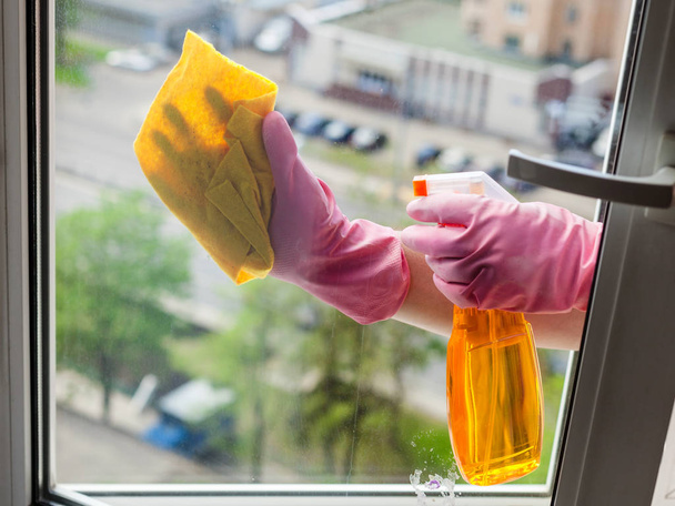 Fenster waschen - Putzfrau reinigt Fensterscheibe mit Waschmittel im Mehrfamilienhaus - Foto, Bild