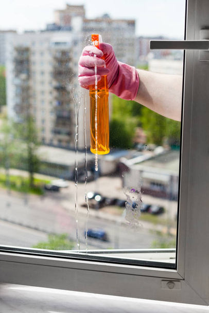 washing home window - washer sprays liquid from spray bottle to window glass in apartment house - Фото, зображення