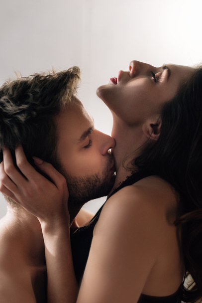 vista lateral do namorado beijando namorada atraente com olhos fechados
  - Foto, Imagem
