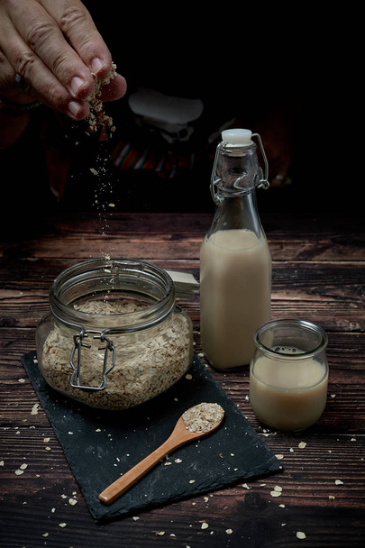 Glass jar full of oatmeal cereal next to a bottle and a glass of oat milk - Foto, Imagem