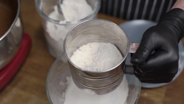 The pastry chef sifts through the flour. In the frame of the hands in black gloves with a sito. Cooking - Séquence, vidéo