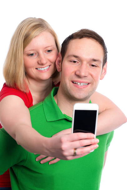 young couple in an embrace in front of white background taking a self portrait - Foto, Bild