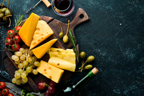 Wine, cheese and snacks on a black stone background. Assorted cheese. Top view. Free space for your text. - Фото, зображення