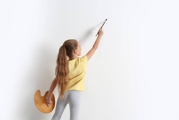 Little child painting on blank white wall indoors, space for text - Foto, Bild
