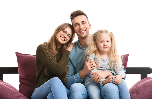 Onnellinen nuori perhe istuu sohvalla valkoista taustaa vasten
 - Valokuva, kuva