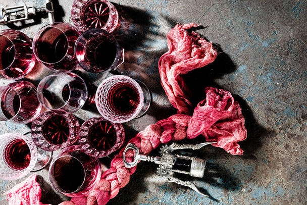 top view of glasses of red wine and corkscrews on grey background - Zdjęcie, obraz