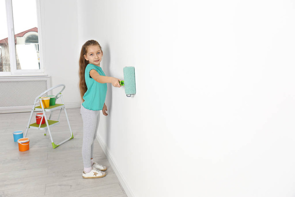 Little child painting with roller brush on white wall indoors. Space for text - Fotoğraf, Görsel