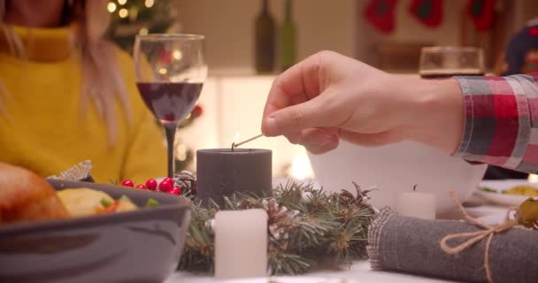 Close-up male hand lighting a candle with a match Christmas dinner family comfort reunion - Filmagem, Vídeo