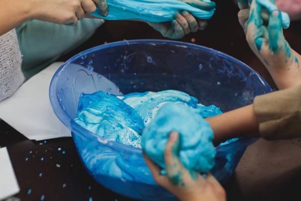 Group of kids making a multicoloured slime, pink, blue and white slime toy on kids birthday party, kid playing with slime, homemade slime - Foto, Imagem