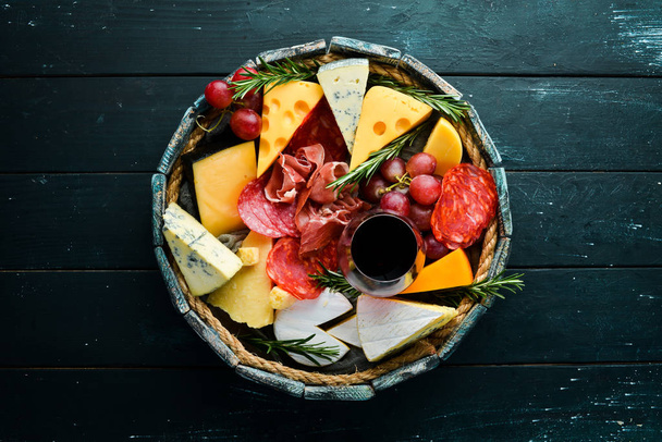 Italian appetizers. Cheese, wine, salami and prosciutto on a black stone background. Top view. Free space for your text. - Fotoğraf, Görsel