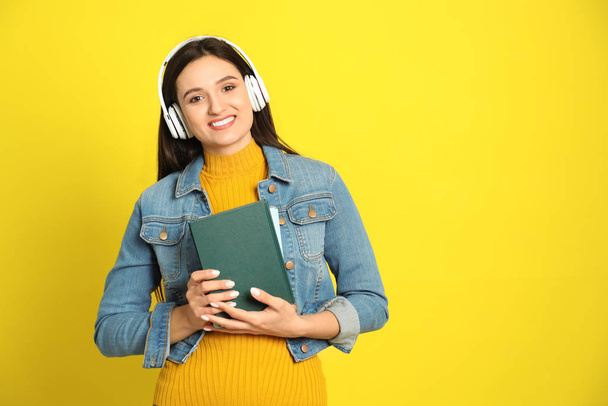 Young woman listening to audiobook on yellow background. Space for text - Foto, Bild