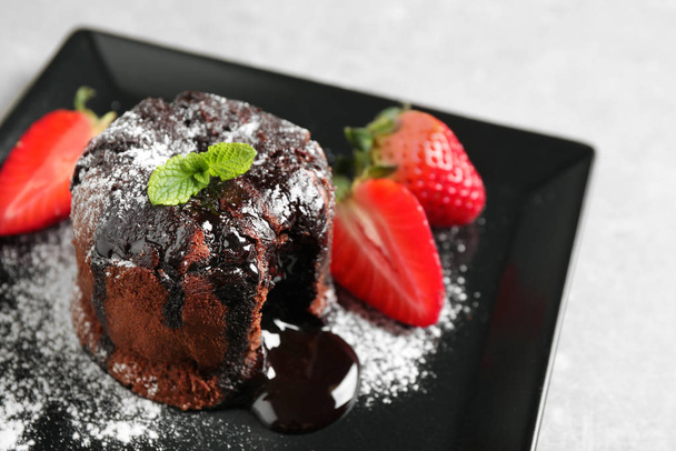 Delicious warm chocolate lava cake with mint and strawberries on plate, closeup - Foto, Imagem