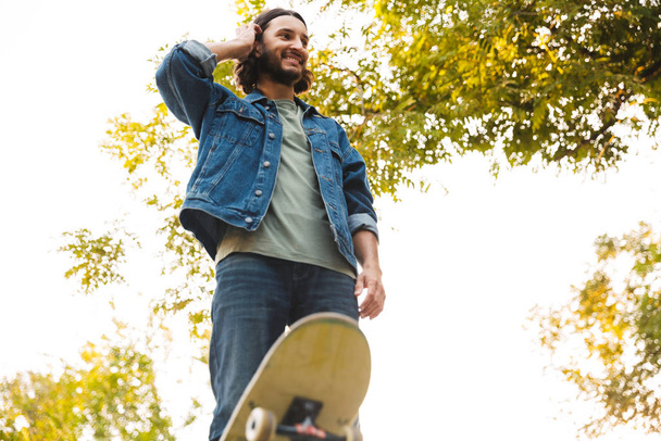 Handsome young hipster man skating on a skate ramp - 写真・画像