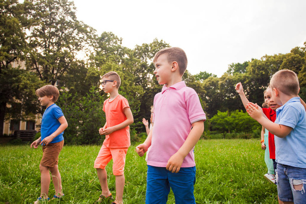 Group of happy kids playing games on green field outdoors - 写真・画像