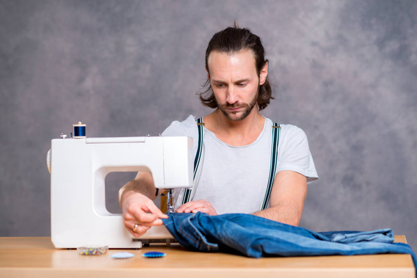 young tailor with sewing machine in front of gray background - Foto, Imagem